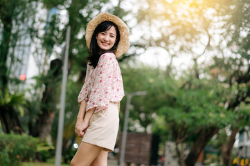 Portrait of asian young woman traveler with weaving hat and basket happy smile on green public park nature background. Journey trip lifestyle, world travel explorer or Asia summer tourism concept.