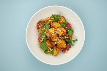 Portion of gourmet crispy fried eggplant salad on blue background