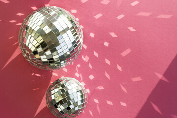 Disco ball on a pink background with shadows and highlights of bright sunlight. Abstract holiday background.