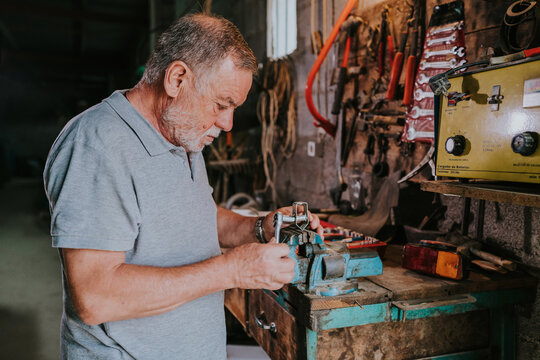 Senior man fixing metal detail with ratchet and vise