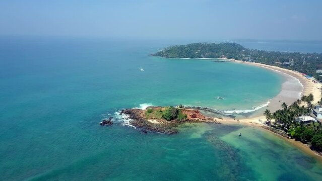 Motorboat sails from deep ocean to beach of tropical island proposing fishing diving or walk-around for tourists aerial view