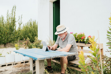 Aged farmer using tablet in garden