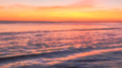 Blurred twilight sunset sky and sea natural background. Abstract dark orange night blur defocused sea beach background.