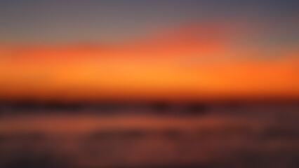 Blurred twilight sunset sky and sea natural background. Abstract dark orange night blur defocused sea background.