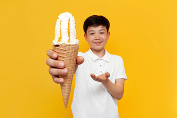 little asian boy offering ice cream on yellow background, korean child giving and recommending...