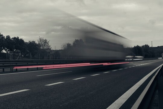 A truck driving on the highway at dusk. Motion blur on the highway. Evening shot of a truck. Concept of international transport and logistics. Almost monochrome image.