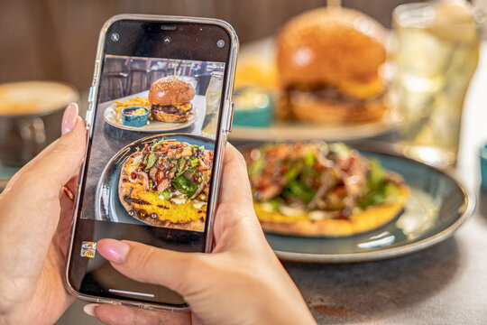 girl hand Taking photo og burger on cellphone in restaurant