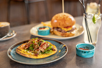 burger and kebab on bread with sauces served on the table in the restaurant