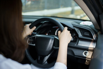 Unrecognizable female car driver holding on a steering wheel close up.