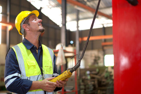 Factory worker - technician controlling a heavy crane in factory close up at his hands holing a crane controller.