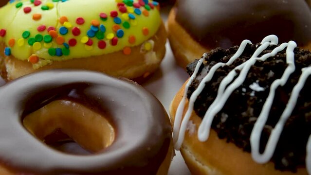 Chocolate, marshmello and candy donuts on a retro baking tray. Donuts are on a paper decorated with natural chocolate. Macro and slider shooting. Various colorful donuts. Chocolate, pink donuts.