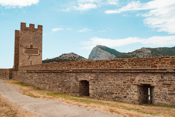 Fototapeta na wymiar A large wall with a tower against a light blue sky.