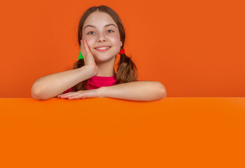 glad child behind blank orange paper with copy space for advertisement