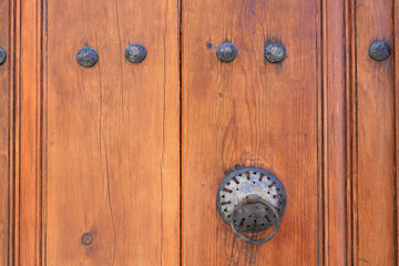 Vintage metal handle on old brown wooden door with metal rivets very close front view