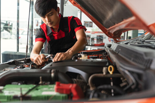 Young Asian male employee repairing and checking engine operation, employee repairing engine, car repair using diagnostic technology