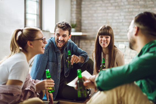 Group of happy friends having fun at home while drinking beer