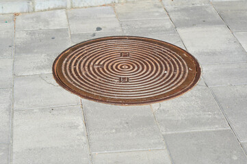 Fototapeta na wymiar metal grate manhole sewer on the street,