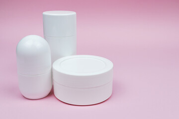 Set of white plastic cosmetic deodorants and jar mock-up on the pink background. Skincare and body care concept, cosmetics, beauty industry.