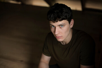 Obraz premium Portrait of a handsome, serious young man of 18 years old, he is resting and thinking about the choice of profession. A serious, slightly sad boy with dark hair and beautiful eyes