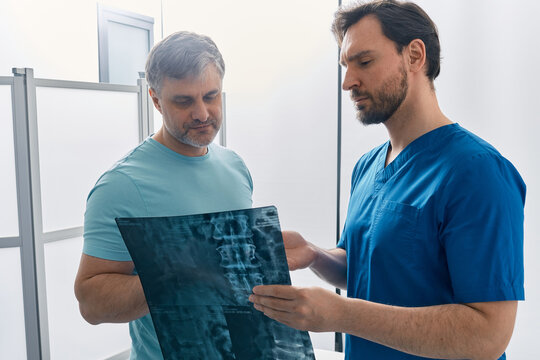 Doctor showing MRI image of spine to patient during medical consultation for analysis and treatment of back disease. Examination and treatment of back pain