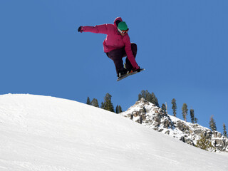 Naklejka na ściany i meble Teenager jumping high on a snowboard at the ski resort