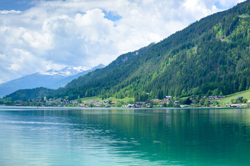 Obraz premium View of the Weissensee lake and a low mountain with a cloudy sky