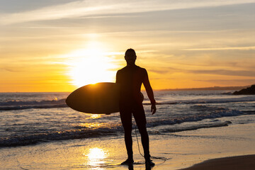 Silhouette of a man surfer on the seashore