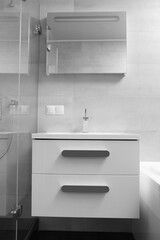 White washbasin with a cabinet and a mirror in the interior of the bathroom.