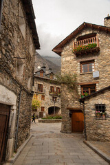 View of the streets of the tourist village of Benasque, in Huesca, Aragon, small stone houses with slate roofs and pedestrian streets in front of the mountains.