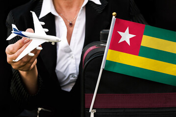 business woman holds toy plane travel bag and flag of Togo
