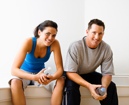 Portrait of young adult woman and man sitting wearing active wear.