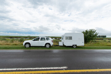 Car transporting a trailer on the side of the road, no people, country scenery