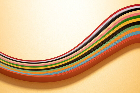 Beautiful curve of strip cut of multi-colored paper on golden textured background with copy space