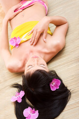Obraz na płótnie Canvas Beautiful asian girl with orchids relaxing in spa salon