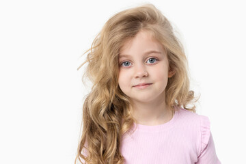 Portrait of a cute baby girl on a white background, holding her hands near her face. Big blue eyes and wavy hair. Blank space for inscription