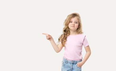 Portrait of a cute baby girl on a white background, points to the left. Big blue eyes and wavy hair. Blank space for inscription