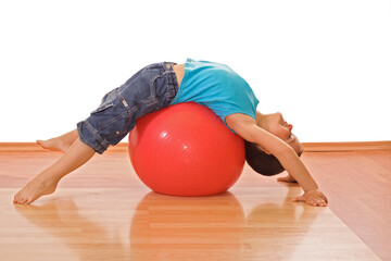 Fototapeta na wymiar Happy little boy stretching on a gymnastic ball - isolated