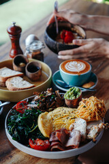 Morning breakfast on a table, waffles with cream, berries, coffee, cappuccino, bowl, omlet with vegetables, bread with butter, avocado cream, vegan food, healthy food, meal. - obrazy, fototapety, plakaty