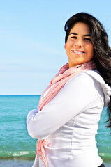 Portrait of beautiful smiling brunette girl at beach with crossed arms