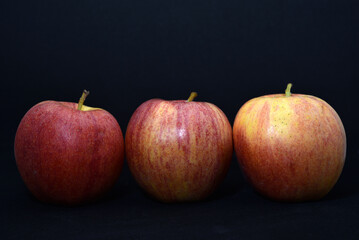 Red and yellow apples on a black background. Delicious apples close-up.