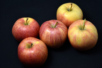 Red and yellow apples on a black background. Delicious apples close-up.