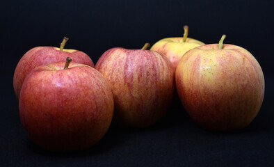 Red and yellow apples on a black background. Delicious apples close-up.