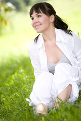 Naklejka na ściany i meble attractive brunette woman relaxing on grass