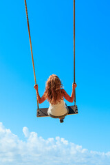 woman on a swing on blue sky- dream, relaxing,freedom concept
