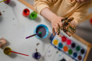 Colourful hands - One toddler girl playing with painting tools and paint with colours, early child education and development, creativity concept 