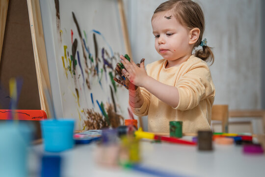 One toddler girl playing with painting tools and paint with colours, early child education and development, creativity concept 
