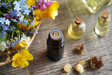 Selection of essential oils with spring flowers and frankincense