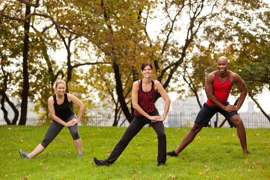 A group of people stretching in a park - focus on front woman