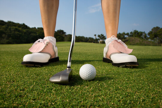 Closeup of a woman golfer about to make a putt. Horizontal shot.