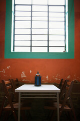 A simple table sitting under a window against a rustic wall. Vertical shot.